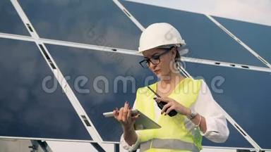 女工程师正站在太阳能电池板旁用对讲机交谈。 替代能源概念